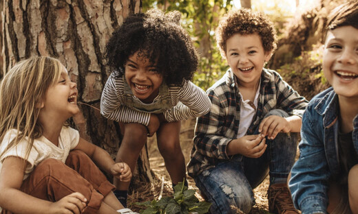 group of cute kids sitting together in forest and playing